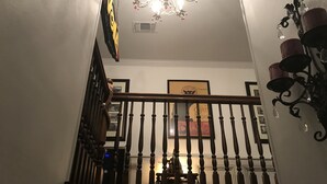 Un escalier orné d’un lustre et de plusieurs appliques murales.