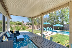 A covered patio area with a pool, outdoor seating, and a view of the backyard.