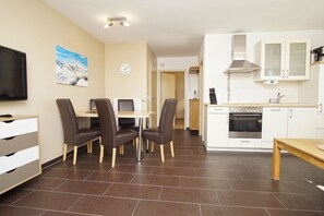 Eine moderne Küche mit weißen Schränken, einem Einbauofen und einem Essbereich mit Tisch und Stühlen.