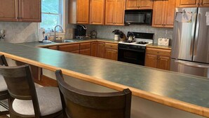 A modern kitchen with wooden cabinets, a stainless steel refrigerator, a microwave, and a gas stove. - Pet Friendly Private Home, Located in Forest Ridge (Lincoln)