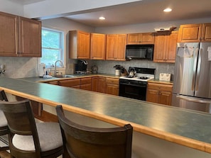 A modern kitchen with wooden cabinets, a stainless steel refrigerator, a microwave, and a gas stove.