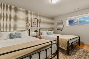 Une chambre avec deux lits, un miroir fixé au mur, un panneau décoratif encadré et une fenêtre donnant sur un paysage agréable.