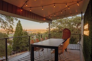 Une terrasse extérieure avec une table et des chaises, des guirlandes lumineuses et une vue sur le paysage.