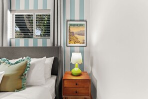 A bedroom with a bed, a nightstand, a lamp, a window with blinds, and a framed picture on the wall. - Epic Game Room, Outdoor Movie Night, Hot Tub, Fire Pit (The Dalles)