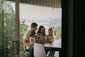 Une famille est assise à une table en plein air, profitant de la vue sur le paysage urbain.