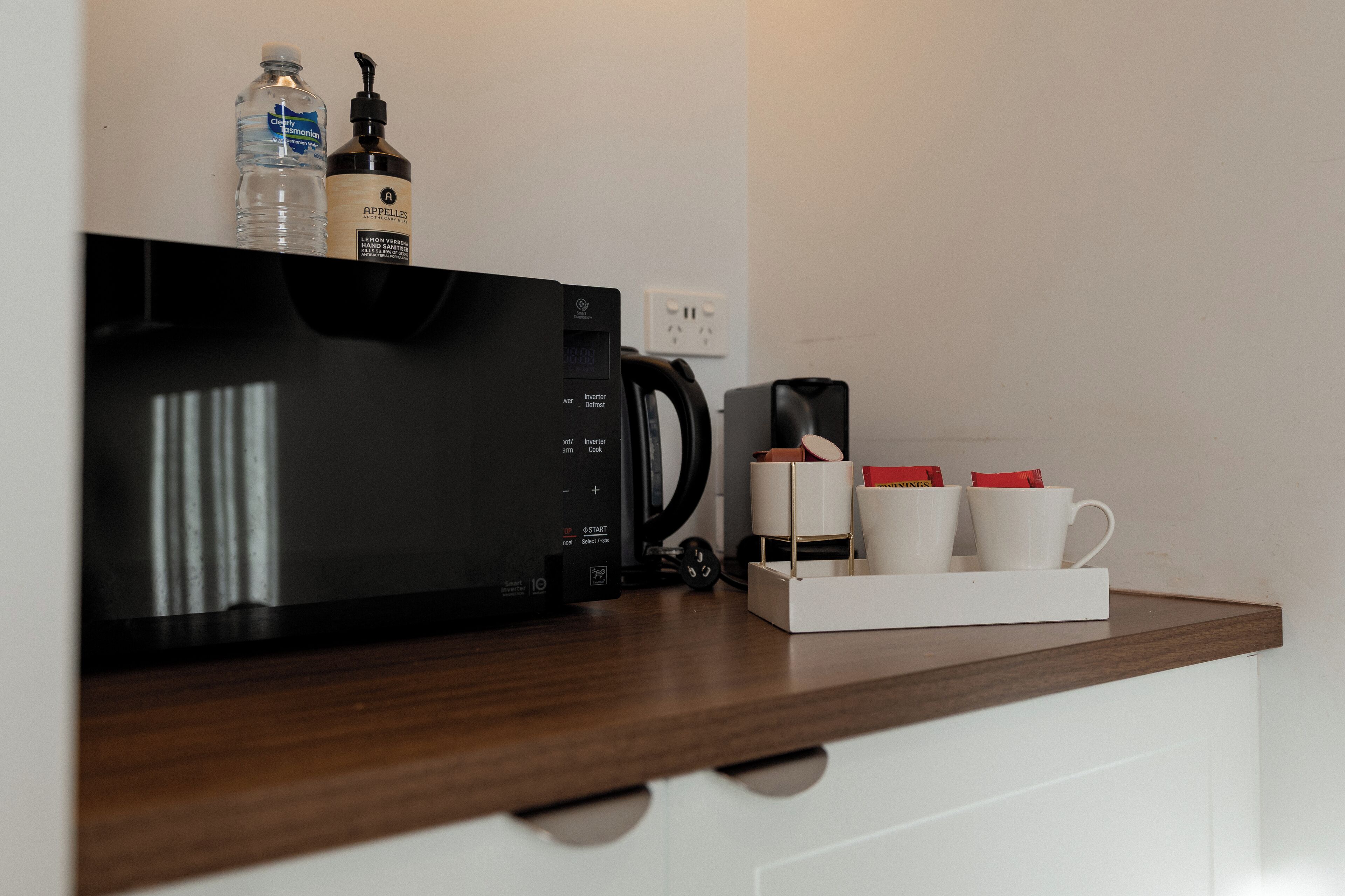 A kitchen counter with a microwave, coffee maker, and a coffee pod holder.