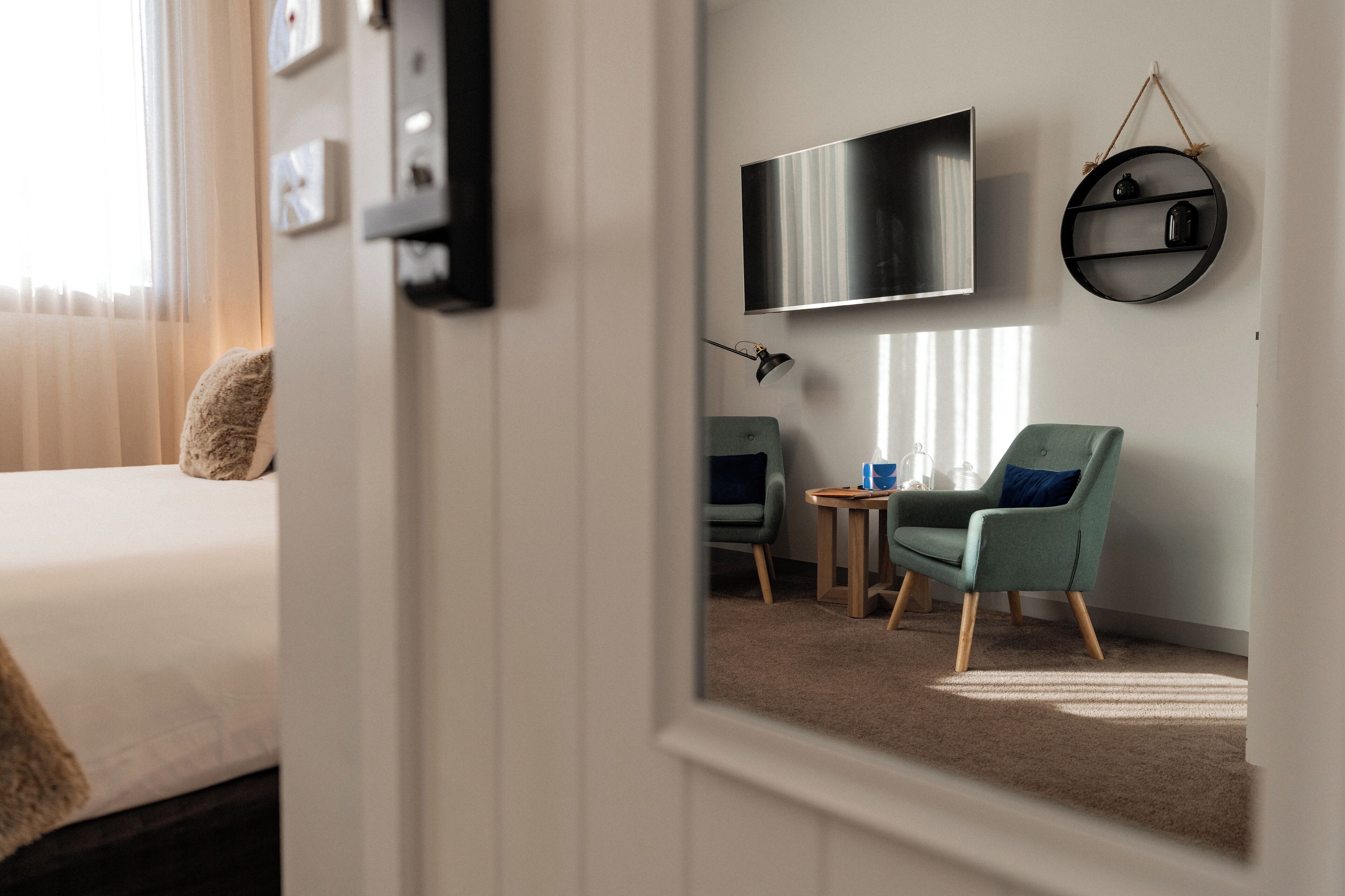 Habitación de hotel con cama, escritorio, silla, televisor y estante con adornos.