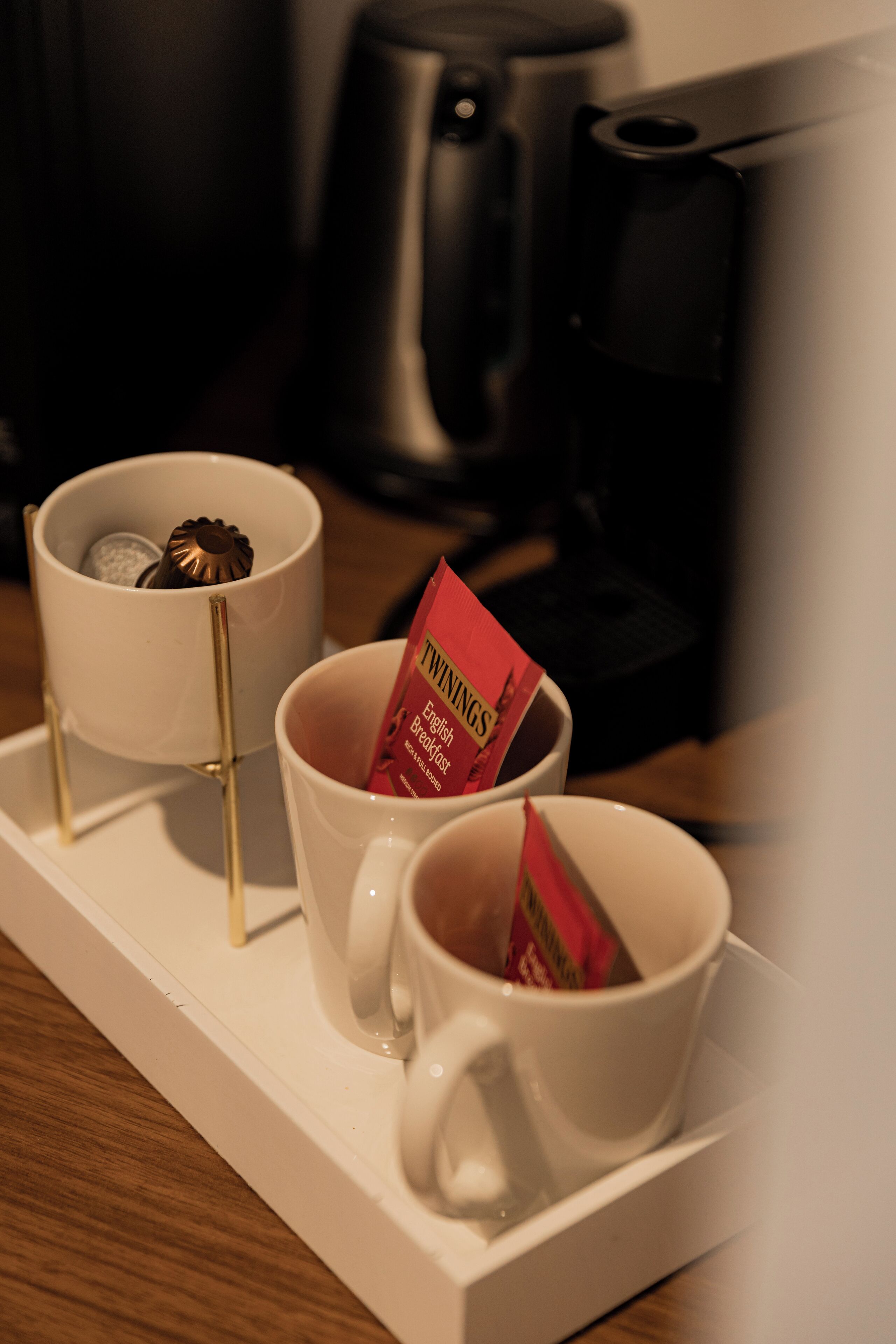 A tray with two white cups, one containing a red packet labeled "TWINGE'S English Breakfast" and the other empty.