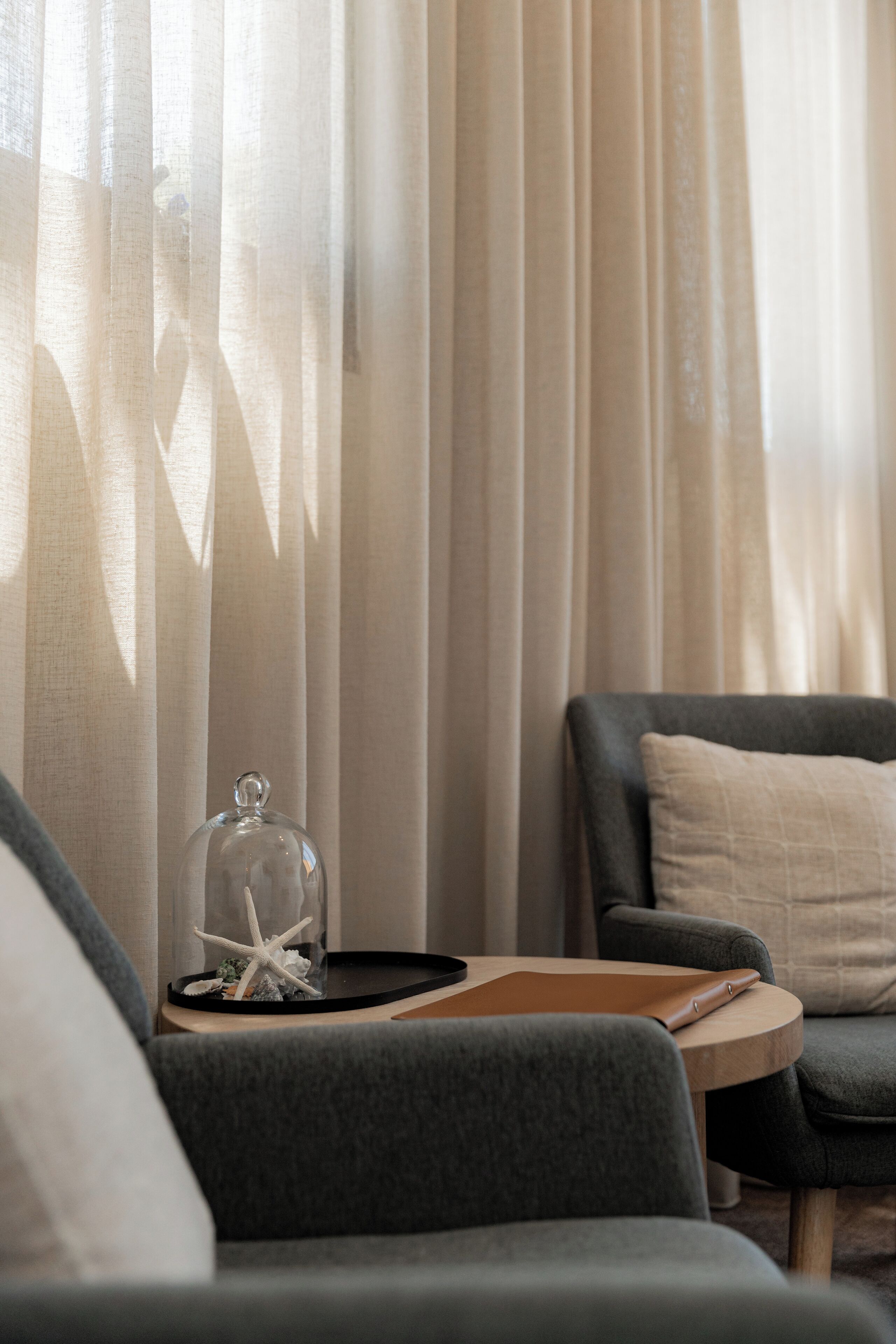 A cozy living room with a grey sofa, a wooden side table, and a glass dome over a decorative item.