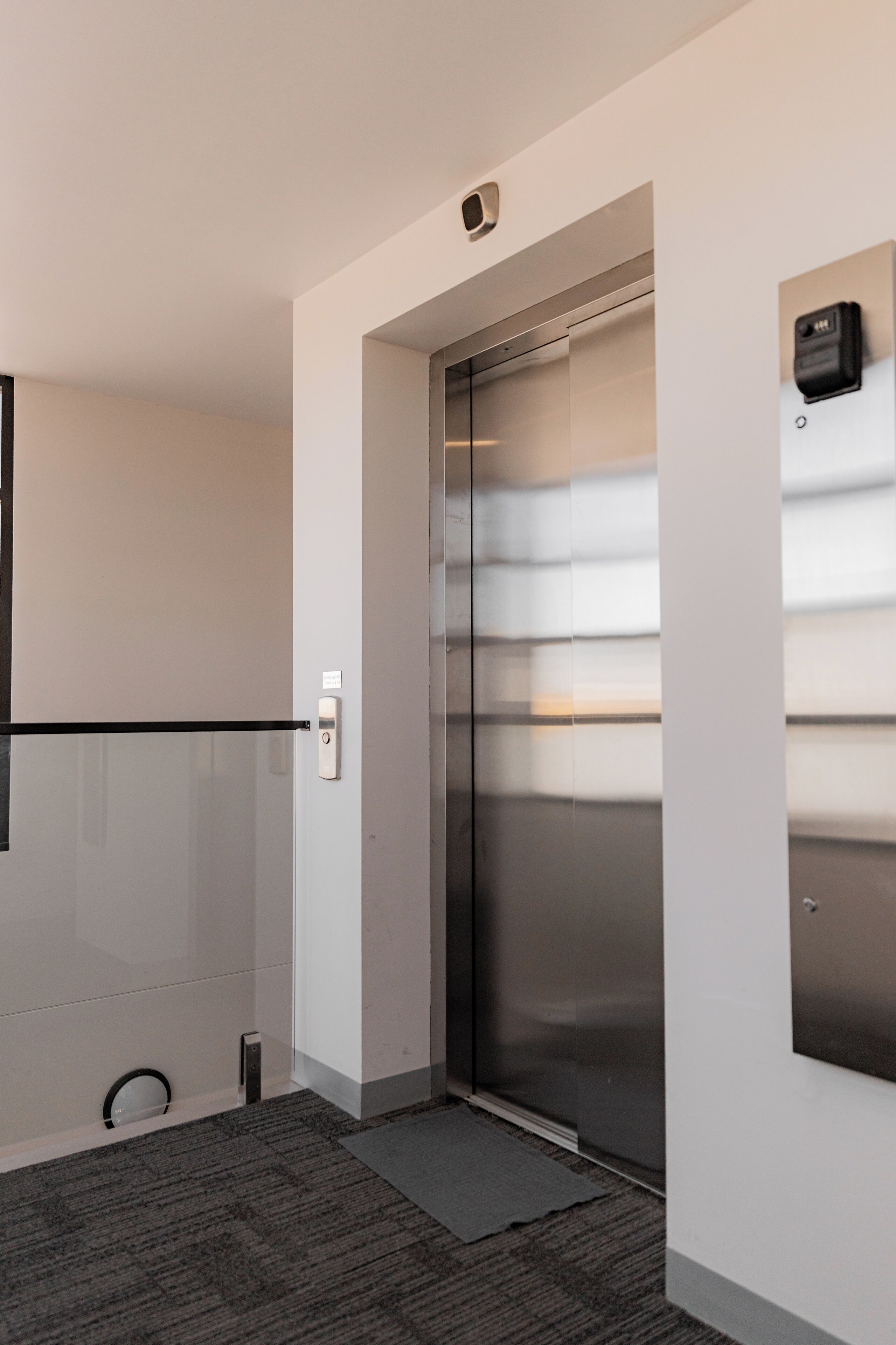 A modern elevator with a metallic finish and a control panel on the wall.