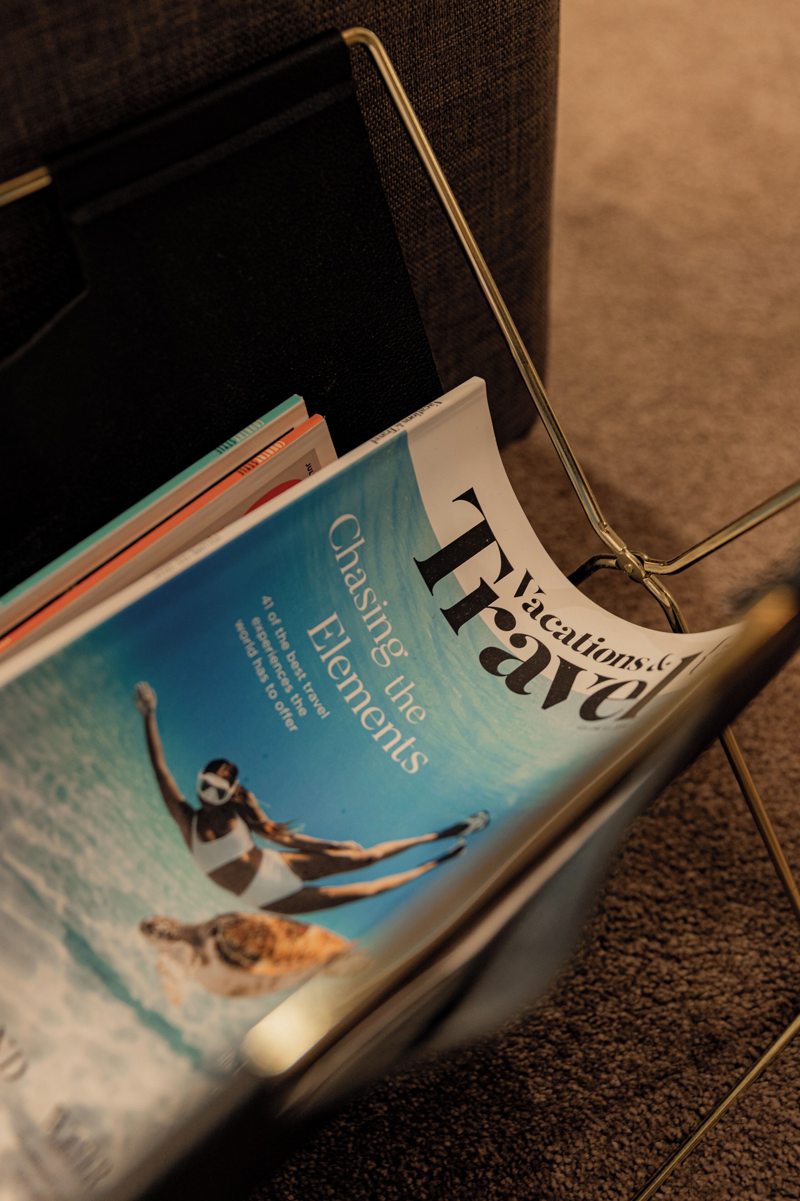 A magazine rack with a 'Travel' magazine featuring a cover with a person diving into the ocean.