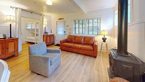 Een ruime woonkamer met een bank, fauteuil en een open haard.
