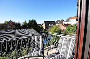 A balcony with a view of houses and a swimming pool.
