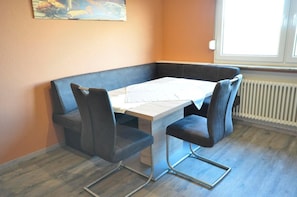 A corner dining area with a white table and black upholstered chairs.