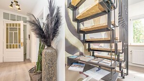 Un interior moderno con una escalera de caracol, un jarrón decorativo con plumas y una puerta con un panel de vidrio.