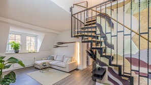 Una sala de estar moderna con un sofá blanco, una mesita de centro y una escalera con barandilla de metal.