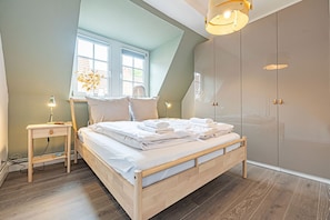 A bedroom with a wooden bed, a nightstand, a mirror, and a wardrobe. - fewo1846 - Seagull view / elegant apartment for 3 pers. on the 4th floor with harbor view (Flensburg)
