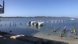 A marina with boats docked, clear water, and a distant shoreline with hills. - Inside of Poblado, this brand new is for you! (Boquerón)