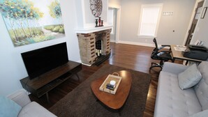 Een woonkamer met een open haard, een flatscreen televisie, een salontafel en een bank.