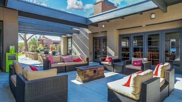 An outdoor patio with wicker furniture, a fire pit, and a covered area with a view of the neighborhood. - Condo in the heart of the Catalina Foothills (Tucson)