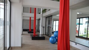 Ein modernes Fitnessstudio mit Holzböden, roter Trainingsausstattung und großen Fenstern mit Blick nach draußen.