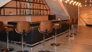 Eine Bar mit Backsteinwand, Regalen voller Flaschen und hängenden Glühbirnen.