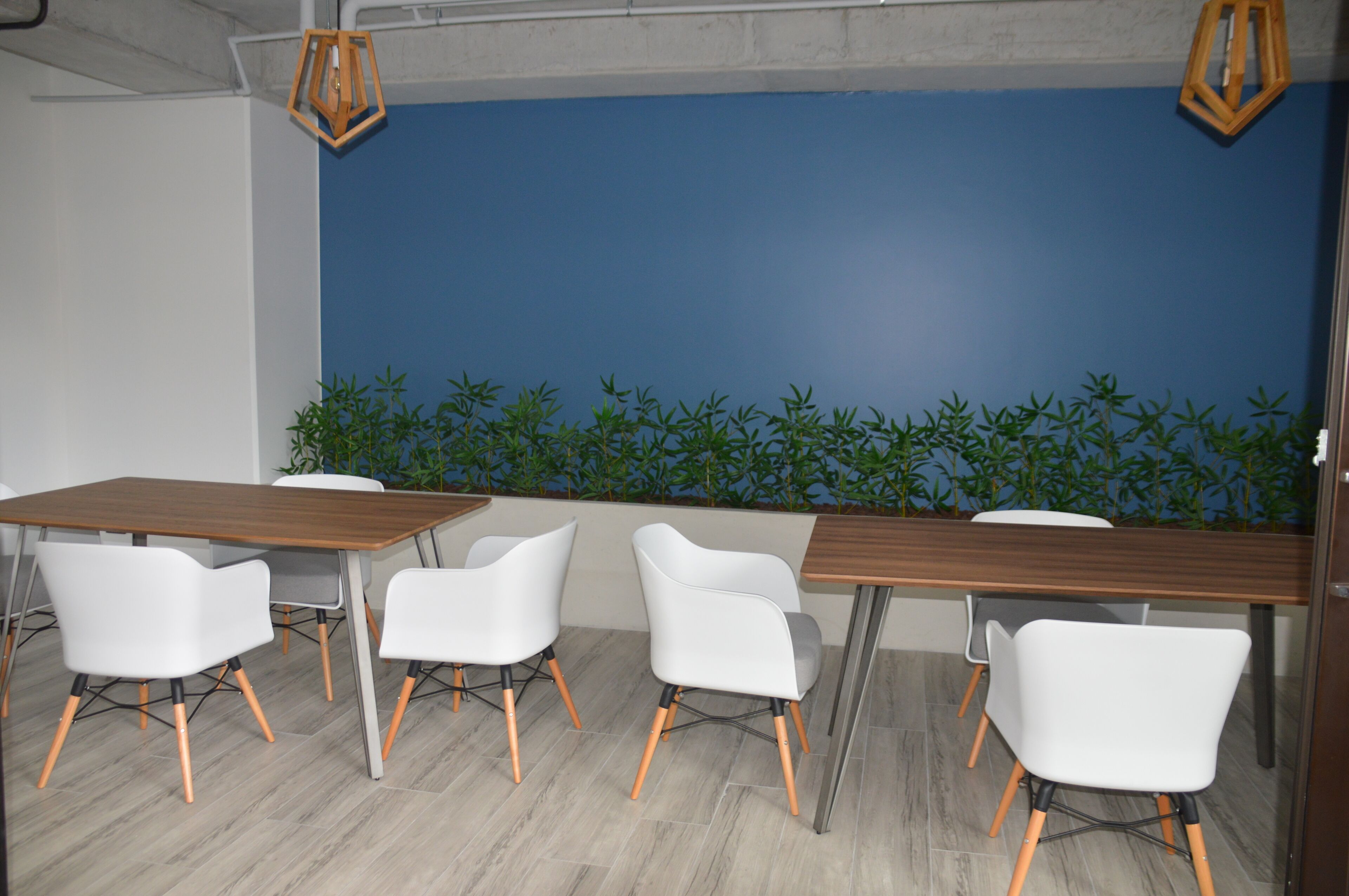 Een moderne vergaderruimte met een blauwe accentmuur, witte stoelen en houten tafels.