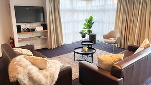 Ein modernes Wohnzimmer mit Flachbildfernseher, zwei Sofas, einem Couchtisch und einer Topfpflanze.