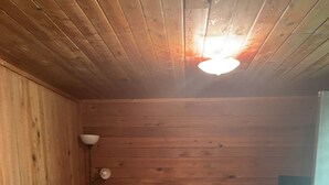 Ett rum med träpanel på väggarna, en soffa, en lampa och en dörr.