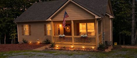 A two-story house with a porch, an American flag, and a wreath.