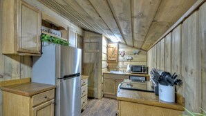 A wooden kitchen with a stainless steel refrigerator, wooden cabinets, a microwave, and a sink. - The Barn with a  Hot Tub, Fire Pit and Pet Friendly (Blue Ridge)