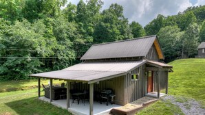 A rustic cabin with a covered porch, a small deck, and a red door. - The Barn with a  Hot Tub, Fire Pit and Pet Friendly (Blue Ridge)