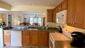 A modern kitchen with wooden cabinets, a built-in microwave, a dishwasher, and a coffee maker.