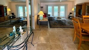 A spacious living area with a dining table, chairs, a sofa, and a TV.