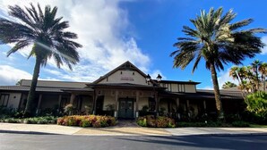 A two-story building with a traditional architectural style, featuring a central entrance with a covered porch and a sign above the door.