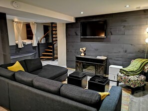 Un salon moderne comprenant un canapé, une table basse, une cheminée, un téléviseur et un escalier.