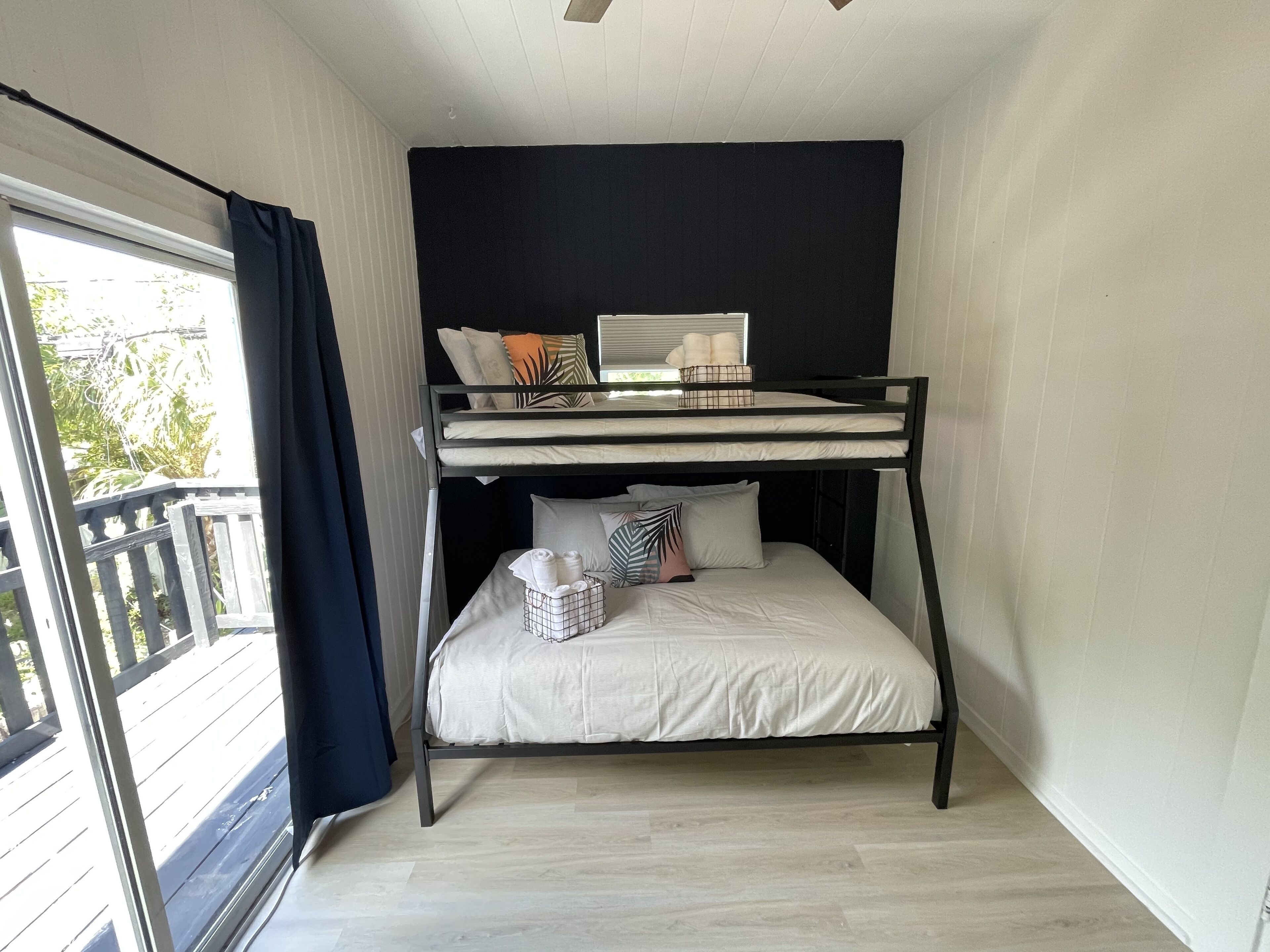 A bunk bed room with a window, a balcony, and a ceiling fan.