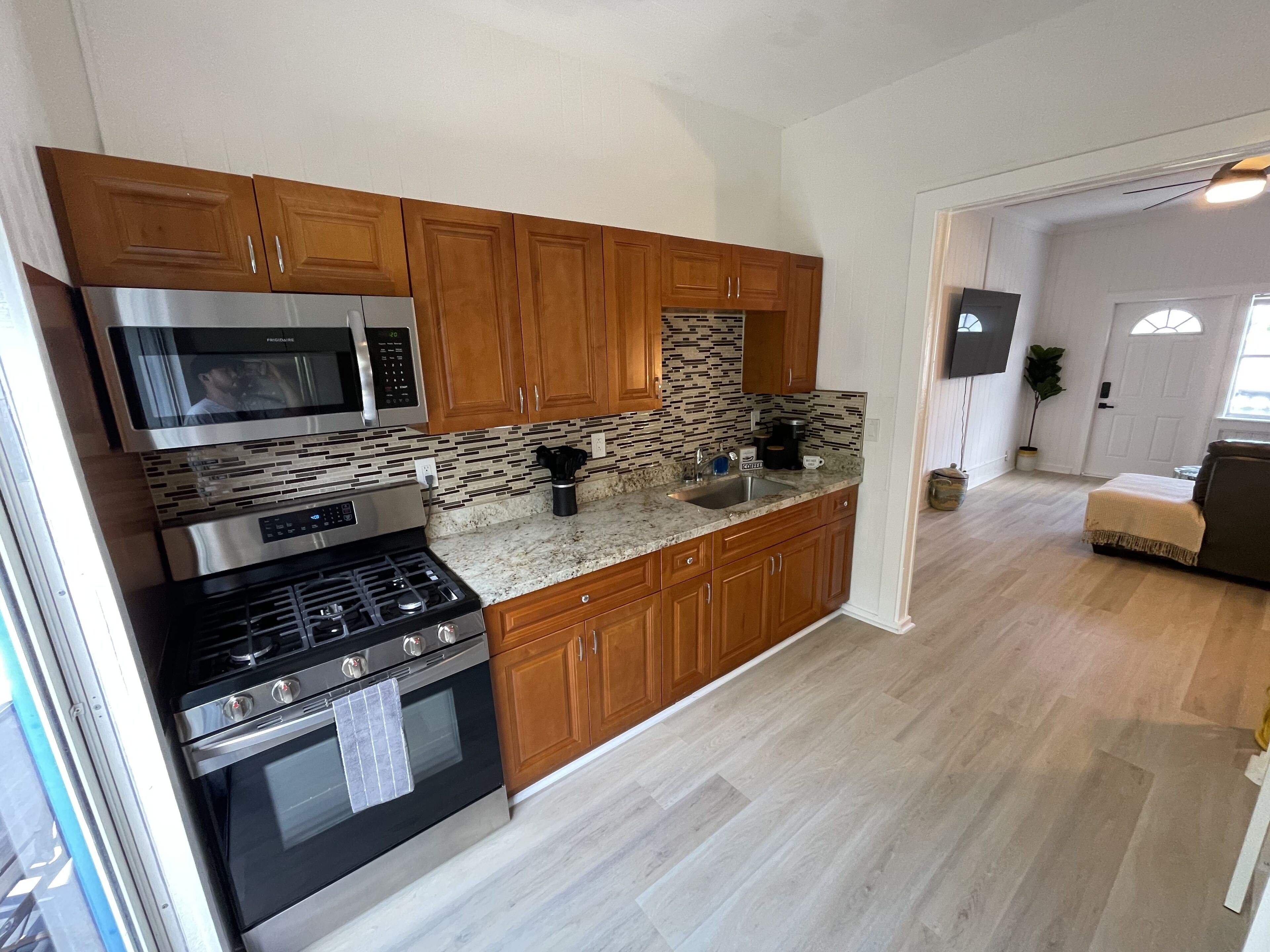 A modern kitchen with wooden cabinets, stainless steel appliances, and a herringbone tile backsplash.