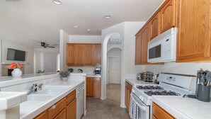 A modern kitchen with wooden cabinets, a white countertop, a microwave, and a stove.