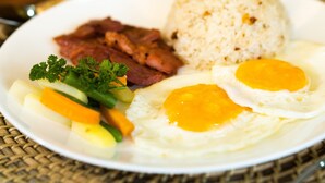 A plate with rice, two fried eggs, and a side of meat and vegetables. - Chambre Hotel Mactan (Lapu-Lapu)