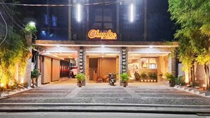A hotel entrance with a neon sign, potted plants, and a motorcycle parked outside. - Chambre Hotel Mactan (Lapu-Lapu)