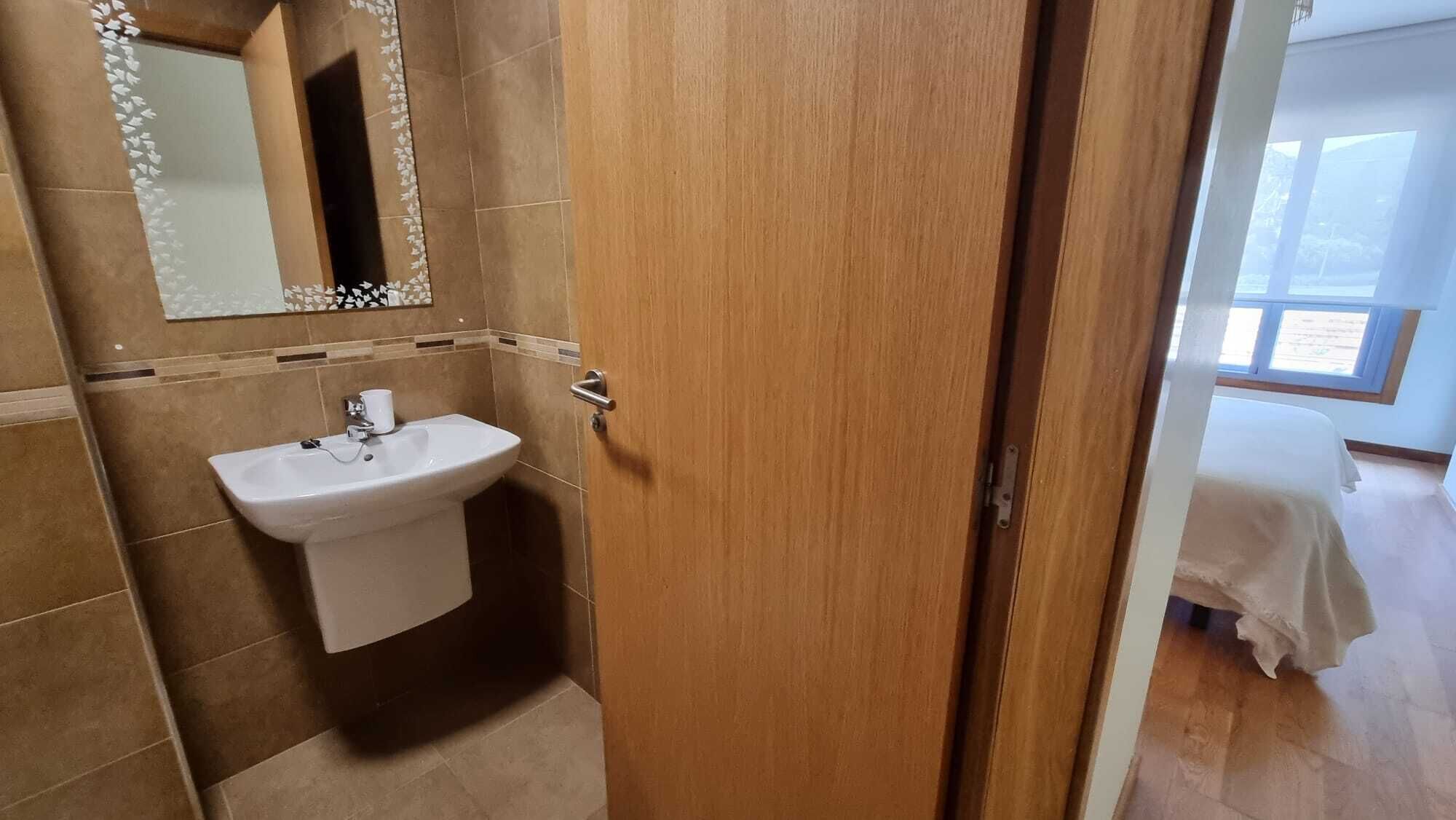 A bathroom with a sink, mirror, and wooden door.