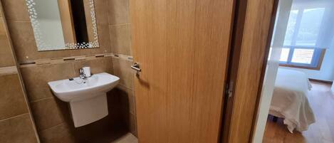 A bathroom with a sink, mirror, and wooden door.
