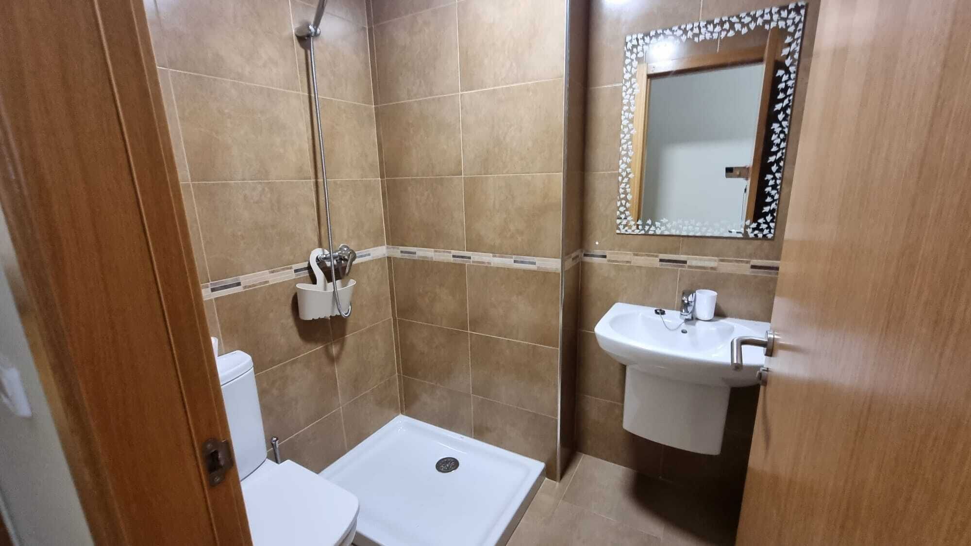 A small bathroom with a shower, toilet, and sink.