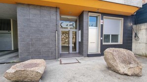 A building entrance with a stone facade, a glass door, and a metal gate.