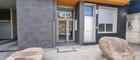 A building entrance with a stone facade, a glass door, and a metal gate.
