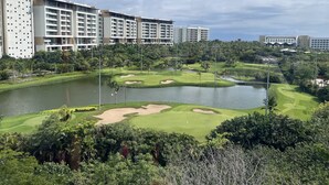 Un parcours de golf avec des bunkers, un étang et un hôtel en arrière-plan.