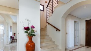 A clean, modern interior with a marble staircase, a wooden chair, and a vase of flowers. - Nice duplex penthouse with the best sea views, luxury urbanization (Marbella)