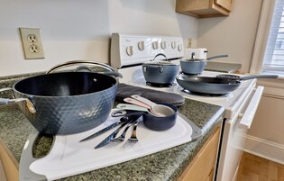 Una cucina con piano cottura bianco, ripiano in granito e diversi utensili da cucina.
