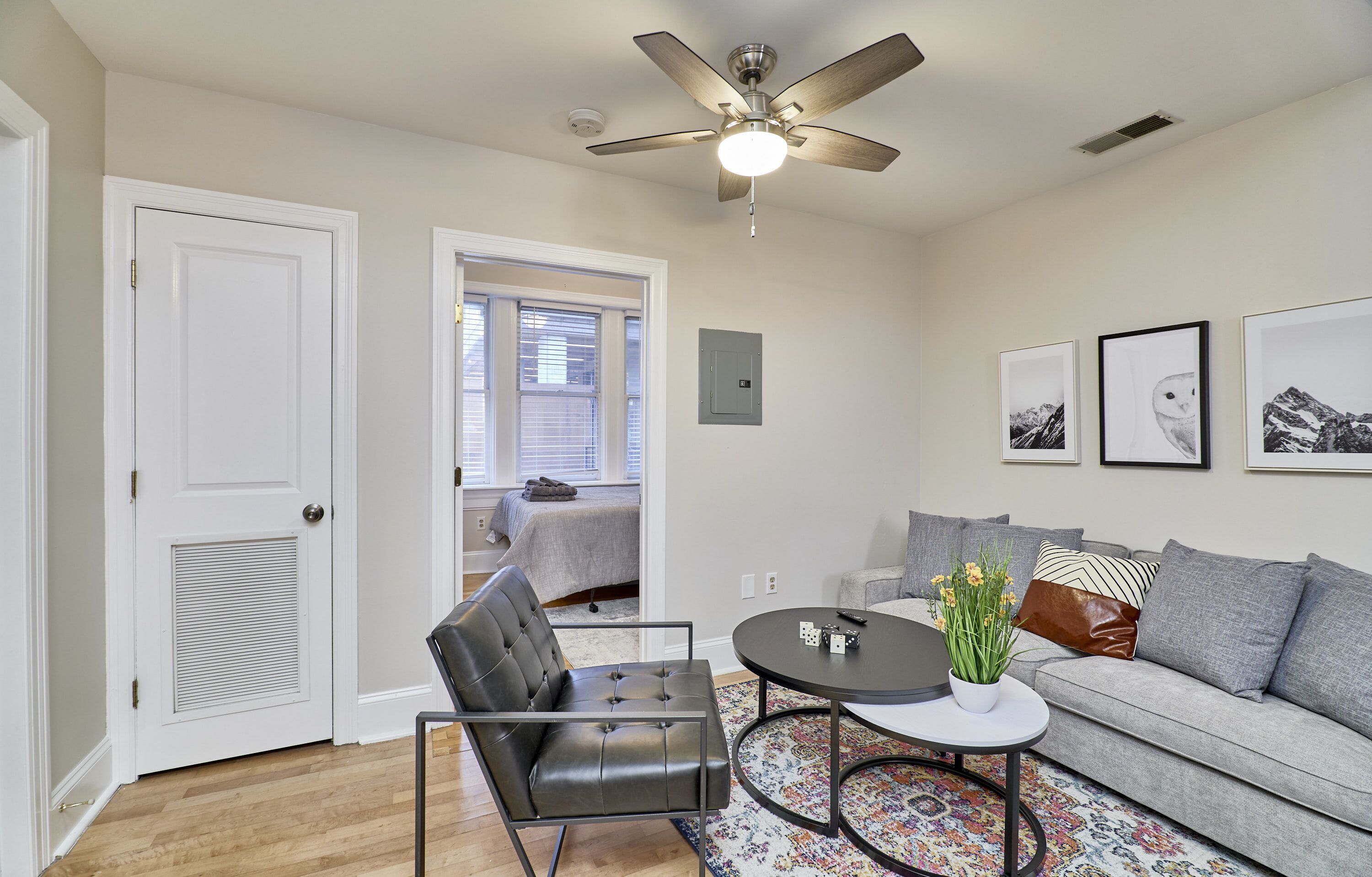 A living room with a sofa, a coffee table, a chair, and a ceiling fan.